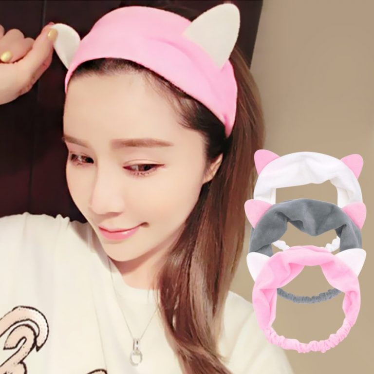 A beautiful, smiling girl wearing a make-up headband shaped as cat ears
